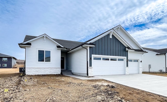 view of front of house with a garage, stone siding, driveway, and board and batten siding