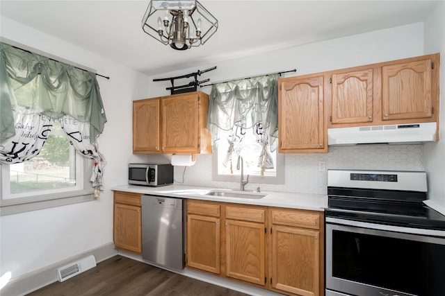 kitchen with dark hardwood / wood-style floors, stainless steel appliances, backsplash, sink, and a notable chandelier