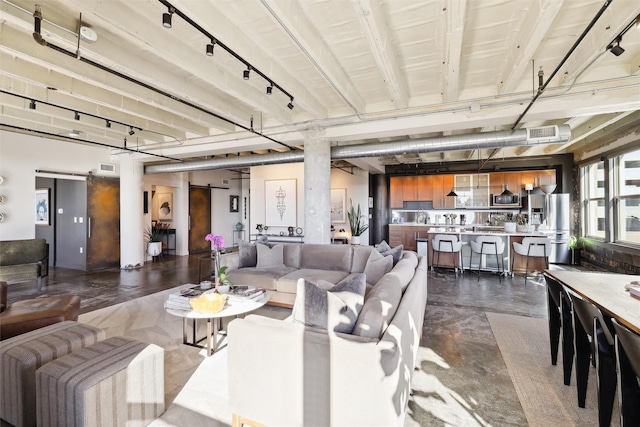 living room featuring a barn door, concrete floors, visible vents, and track lighting