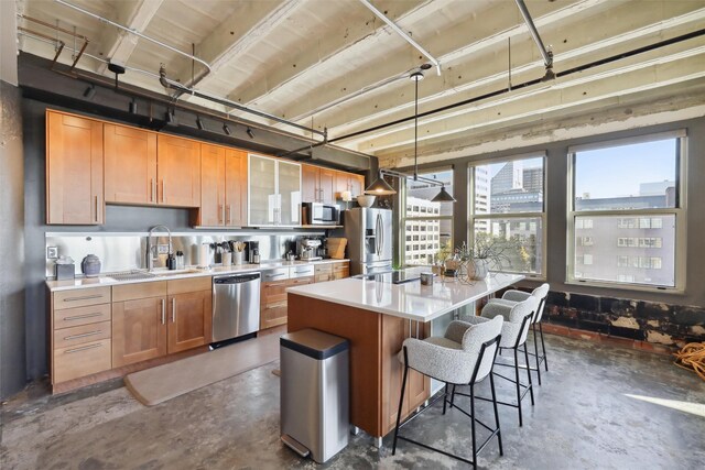 kitchen with a breakfast bar, sink, decorative light fixtures, a kitchen island, and stainless steel appliances