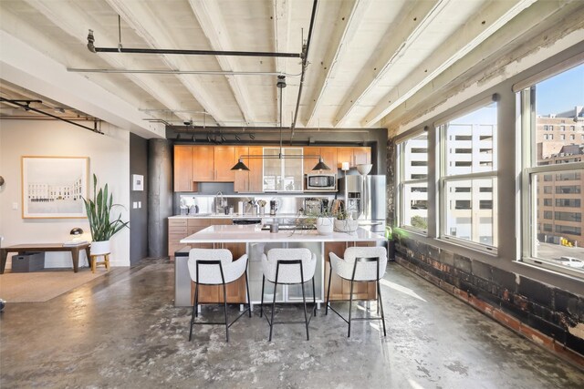 kitchen with a kitchen breakfast bar, sink, hanging light fixtures, a kitchen island, and stainless steel appliances