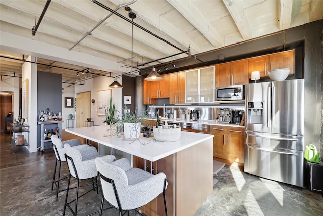 kitchen featuring a breakfast bar, stainless steel appliances, a kitchen island, and hanging light fixtures