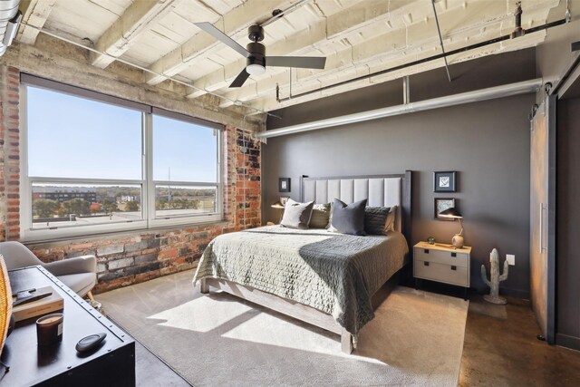 bedroom featuring beamed ceiling, ceiling fan, a barn door, and brick wall