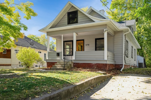 bungalow featuring covered porch, a front lawn, and central air condition unit