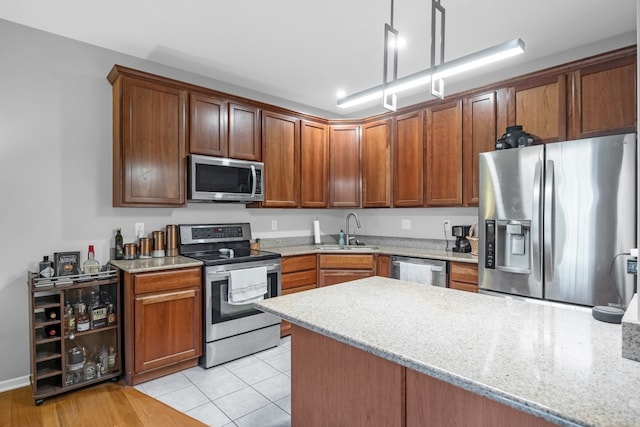 kitchen with sink, appliances with stainless steel finishes, light stone counters, and light hardwood / wood-style floors