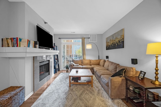 living room with hardwood / wood-style flooring and a tiled fireplace