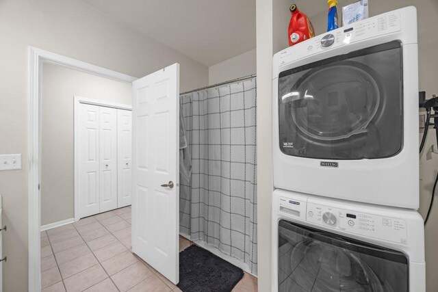 laundry room featuring stacked washer / dryer and light tile patterned flooring