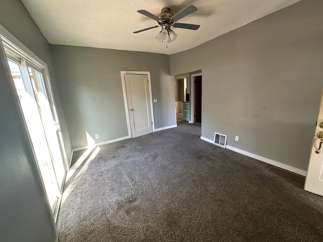 unfurnished room featuring a textured ceiling, dark carpet, and ceiling fan