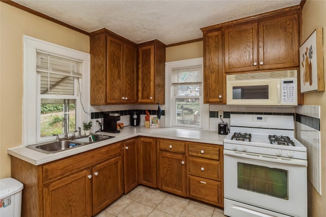 kitchen featuring a textured ceiling, a healthy amount of sunlight, tasteful backsplash, and white appliances