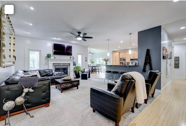 living room with ceiling fan, light carpet, and plenty of natural light