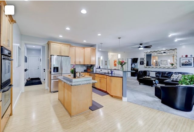 kitchen featuring kitchen peninsula, light brown cabinets, hanging light fixtures, appliances with stainless steel finishes, and sink