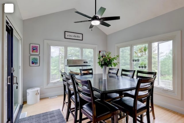 dining area with light hardwood / wood-style flooring, a healthy amount of sunlight, and vaulted ceiling