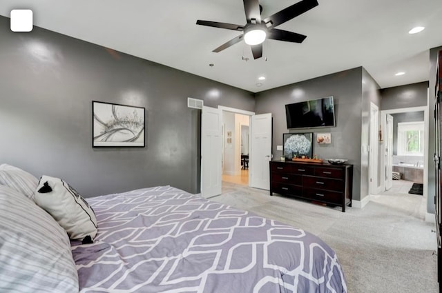 bedroom featuring ensuite bathroom, light carpet, and ceiling fan