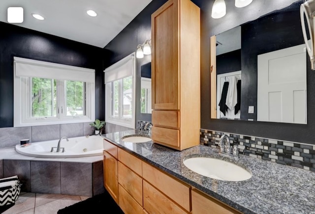 bathroom featuring vanity, a relaxing tiled tub, tile patterned floors, and decorative backsplash