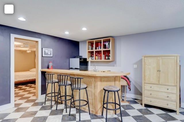 bar featuring sink and black refrigerator