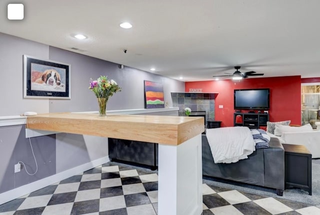 interior space with a tiled fireplace and ceiling fan