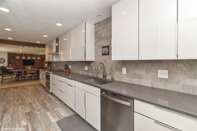 kitchen featuring white cabinetry, sink, wall chimney exhaust hood, appliances with stainless steel finishes, and light wood-type flooring