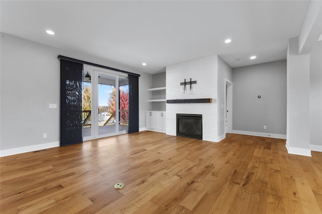 unfurnished living room featuring light hardwood / wood-style flooring and a brick fireplace