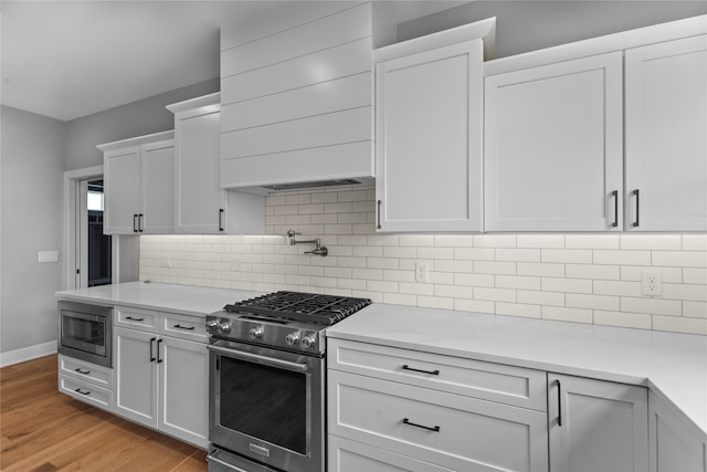 kitchen with decorative backsplash, appliances with stainless steel finishes, light hardwood / wood-style flooring, and white cabinetry