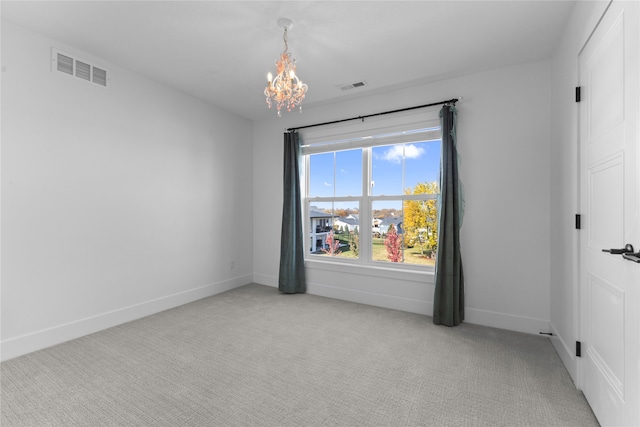 spare room with a chandelier and light colored carpet