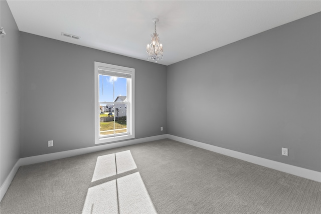 carpeted spare room featuring a chandelier