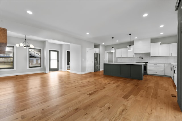 kitchen featuring a kitchen island, light hardwood / wood-style flooring, stainless steel appliances, decorative light fixtures, and white cabinetry