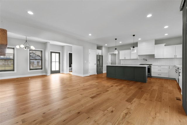675 Daybreak Dr, Waukee, IA 50263 - kitchen featuring an inviting chandelier, appliances with stainless steel finishes, white cabinetry, light wood-type flooring, and open floor plan