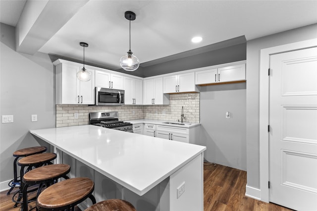 kitchen with sink, kitchen peninsula, stainless steel appliances, decorative light fixtures, and white cabinets