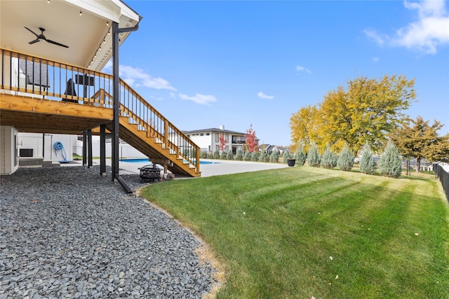 view of yard with a deck with water view, a patio, and ceiling fan