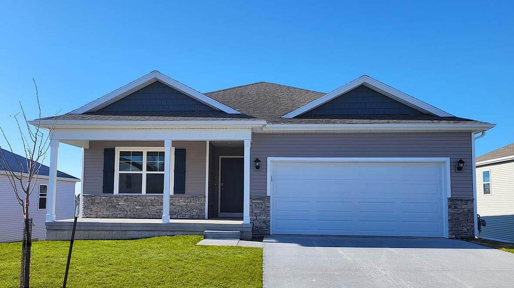 view of front of home featuring covered porch, a front lawn, and a garage