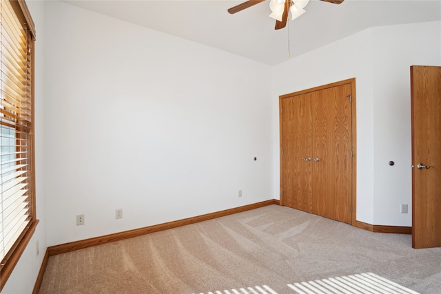 unfurnished bedroom featuring ceiling fan, vaulted ceiling, and light colored carpet