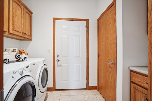 clothes washing area featuring cabinets, light tile patterned floors, and washer and clothes dryer