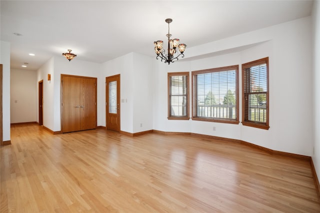 empty room with light hardwood / wood-style flooring and a chandelier