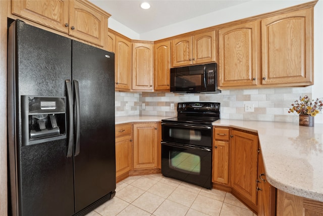 kitchen featuring light tile patterned flooring, tasteful backsplash, black appliances, and light stone countertops