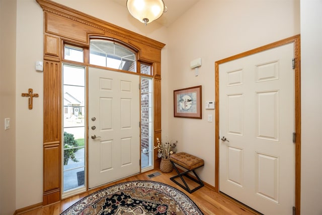 foyer entrance featuring light wood-type flooring, baseboards, and visible vents