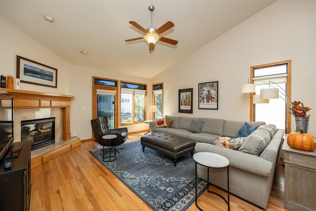 living room featuring high vaulted ceiling, light wood-type flooring, ceiling fan, and a premium fireplace