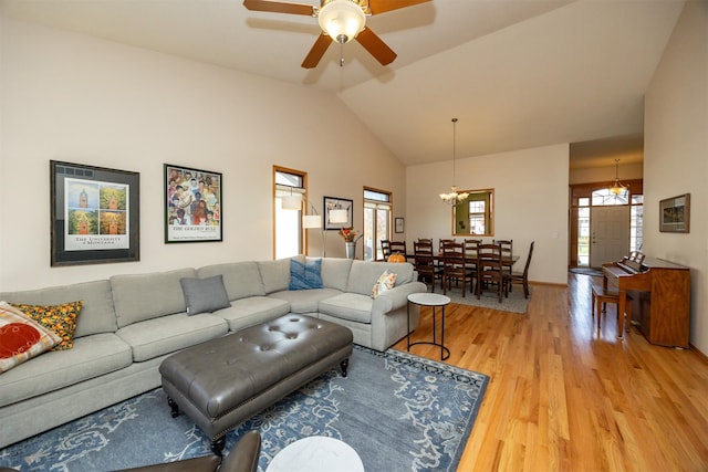 living area with light wood-style flooring, baseboards, vaulted ceiling, and ceiling fan with notable chandelier