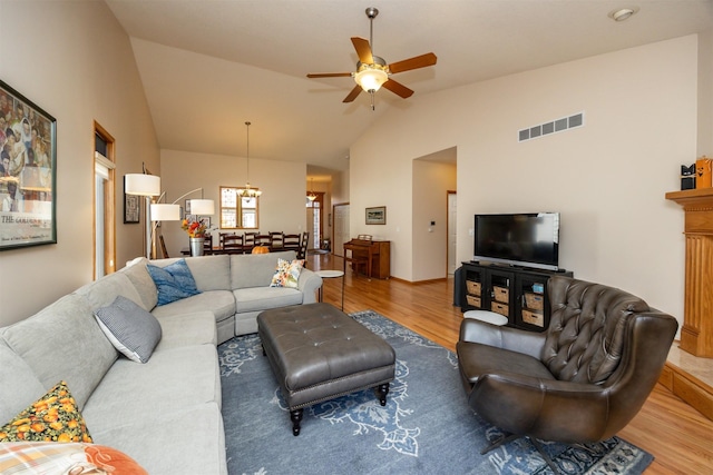 living room with lofted ceiling, wood finished floors, visible vents, and a ceiling fan