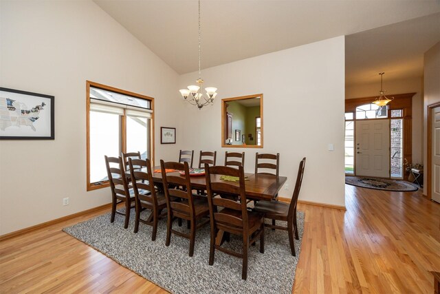 dining area with a notable chandelier, wood-type flooring, and high vaulted ceiling