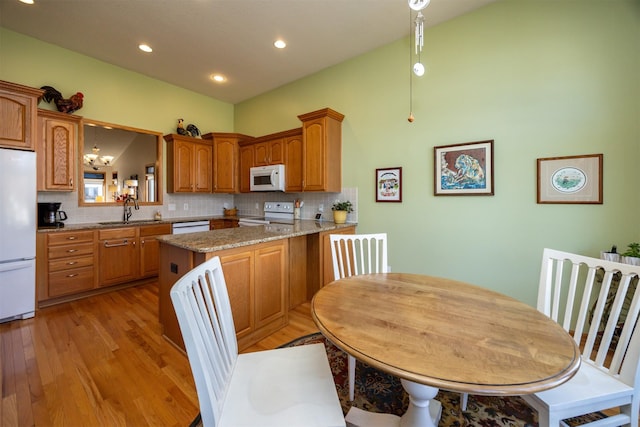 kitchen featuring white appliances, brown cabinets, a sink, and decorative backsplash