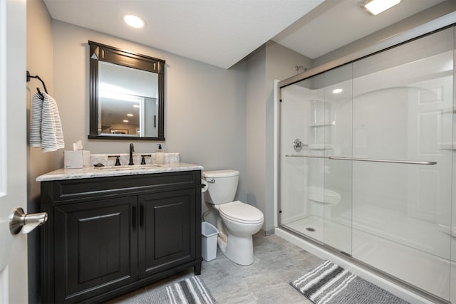 bathroom with a shower stall, toilet, and vanity