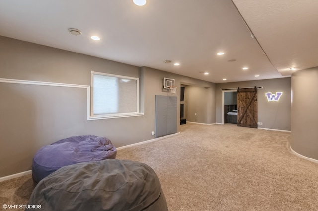 sitting room featuring a barn door and carpet flooring