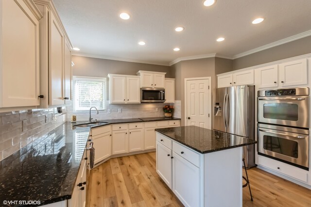 kitchen featuring a kitchen island, light hardwood / wood-style flooring, sink, white cabinets, and appliances with stainless steel finishes