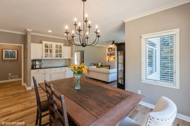 dining space with ornamental molding, light hardwood / wood-style flooring, and ceiling fan with notable chandelier