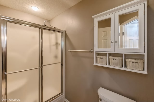 bathroom featuring toilet, a textured ceiling, and walk in shower