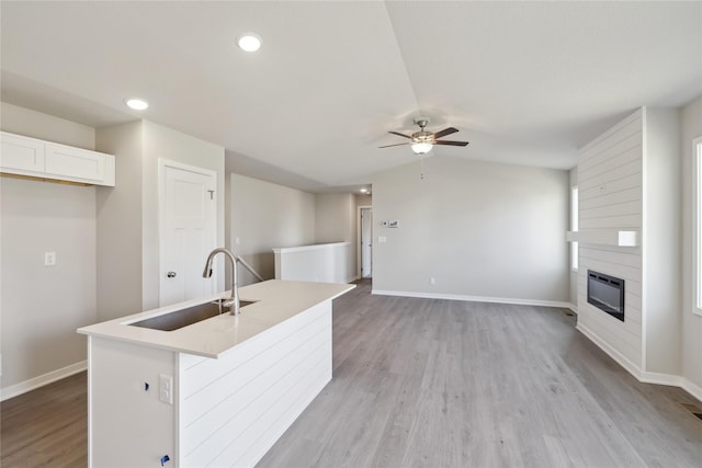 kitchen featuring a fireplace, a sink, vaulted ceiling, light wood-type flooring, and heating unit