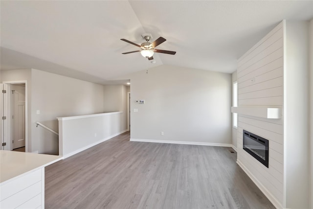 unfurnished living room featuring light wood-style floors, lofted ceiling, a fireplace, and heating unit