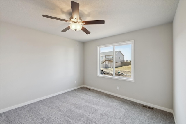 spare room featuring carpet floors, baseboards, visible vents, and ceiling fan