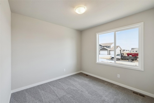 empty room featuring carpet floors, visible vents, and baseboards