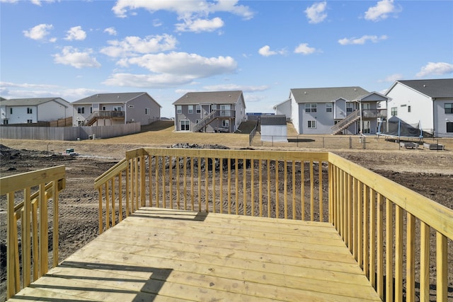 wooden deck with a trampoline, a residential view, a fenced backyard, and stairway